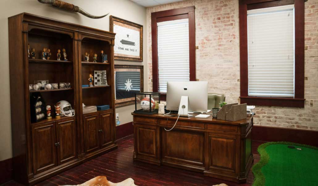 A private office at Heritage featuring a wood desk and a framed Texas "Come and Take It" flag